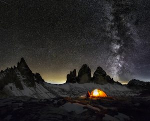 An illuminated tent in Dolomites under Milky Way at the Cime of the Dolomites (Drei Zinnen)