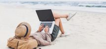 Mann som bruker datamaskin på stranden
