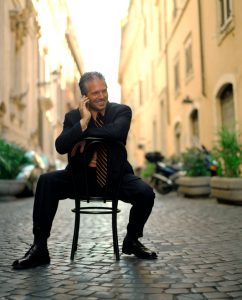 Businessman on cell phone sitting in chair on cobblestone street