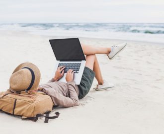 Mann som bruker datamaskin på stranden