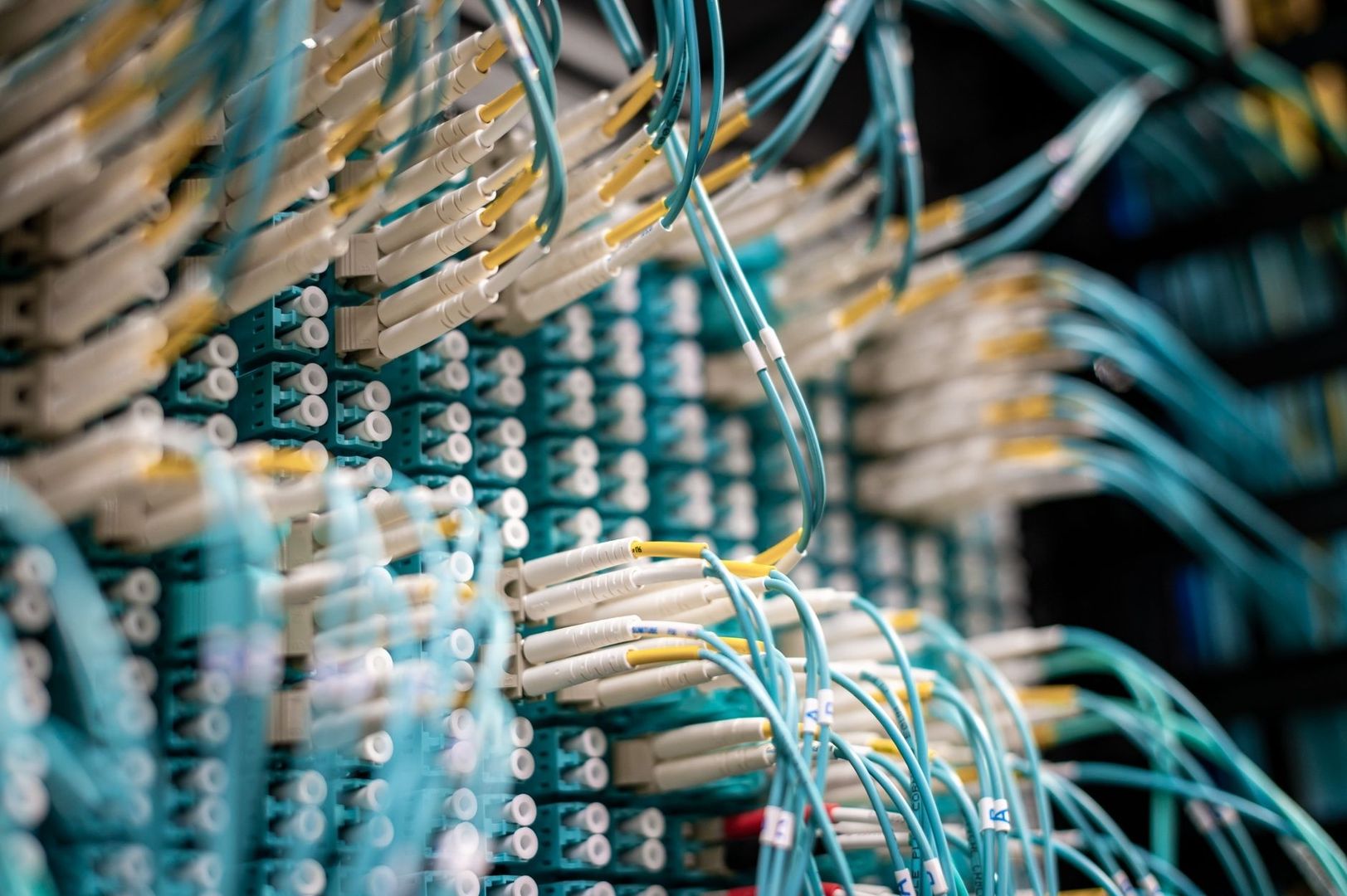 Tettpakket fiberkoblingspanel med turkise og hvite kabler