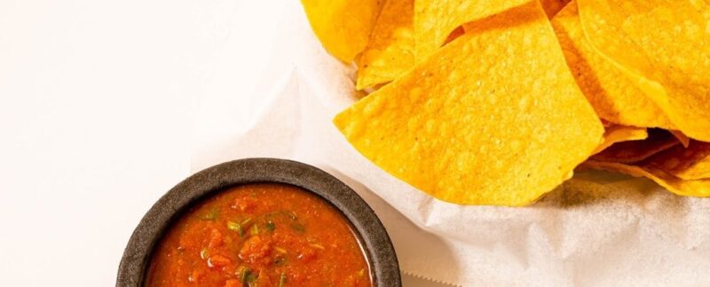 Sprø tortillachips med to skåler rød salsa
