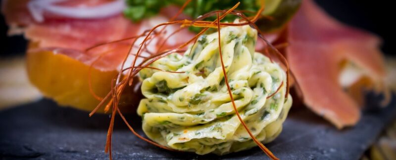 Urtesmør pyntet med sprø tråder på et mørkt serveringsfat